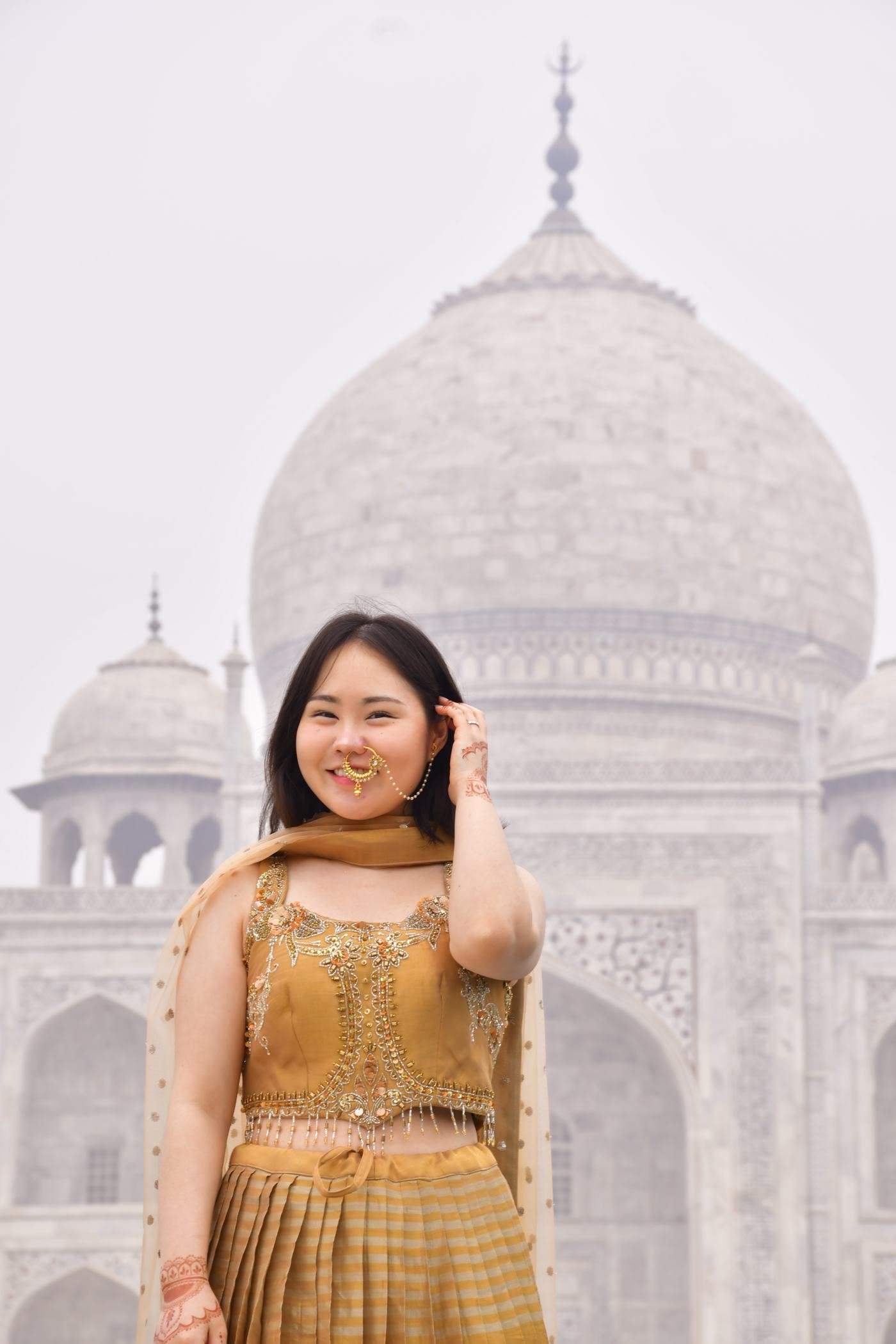 A couple photographed at a red sandstone gateway near the Taj Mahal