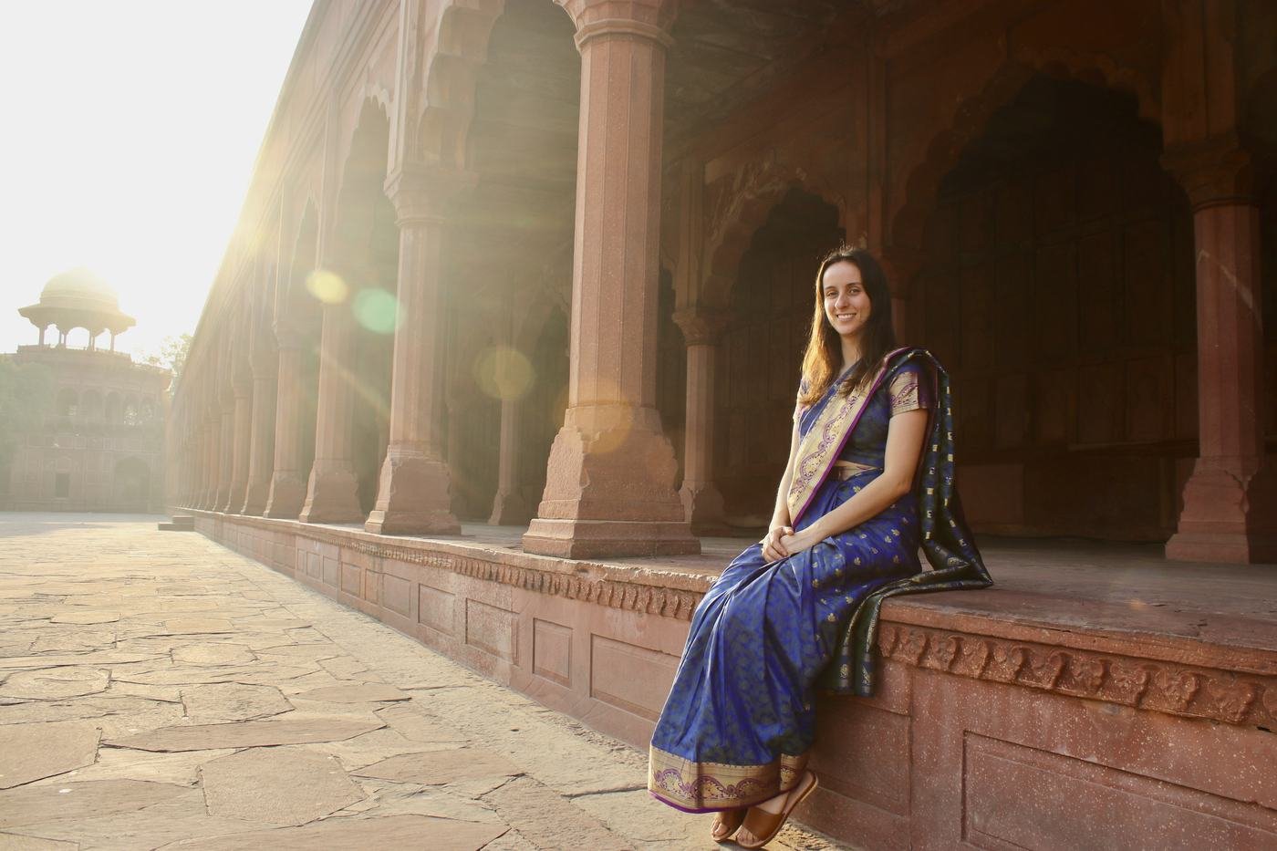 A traveller seated in a sunlit Agra Fort colonnade at golden hour