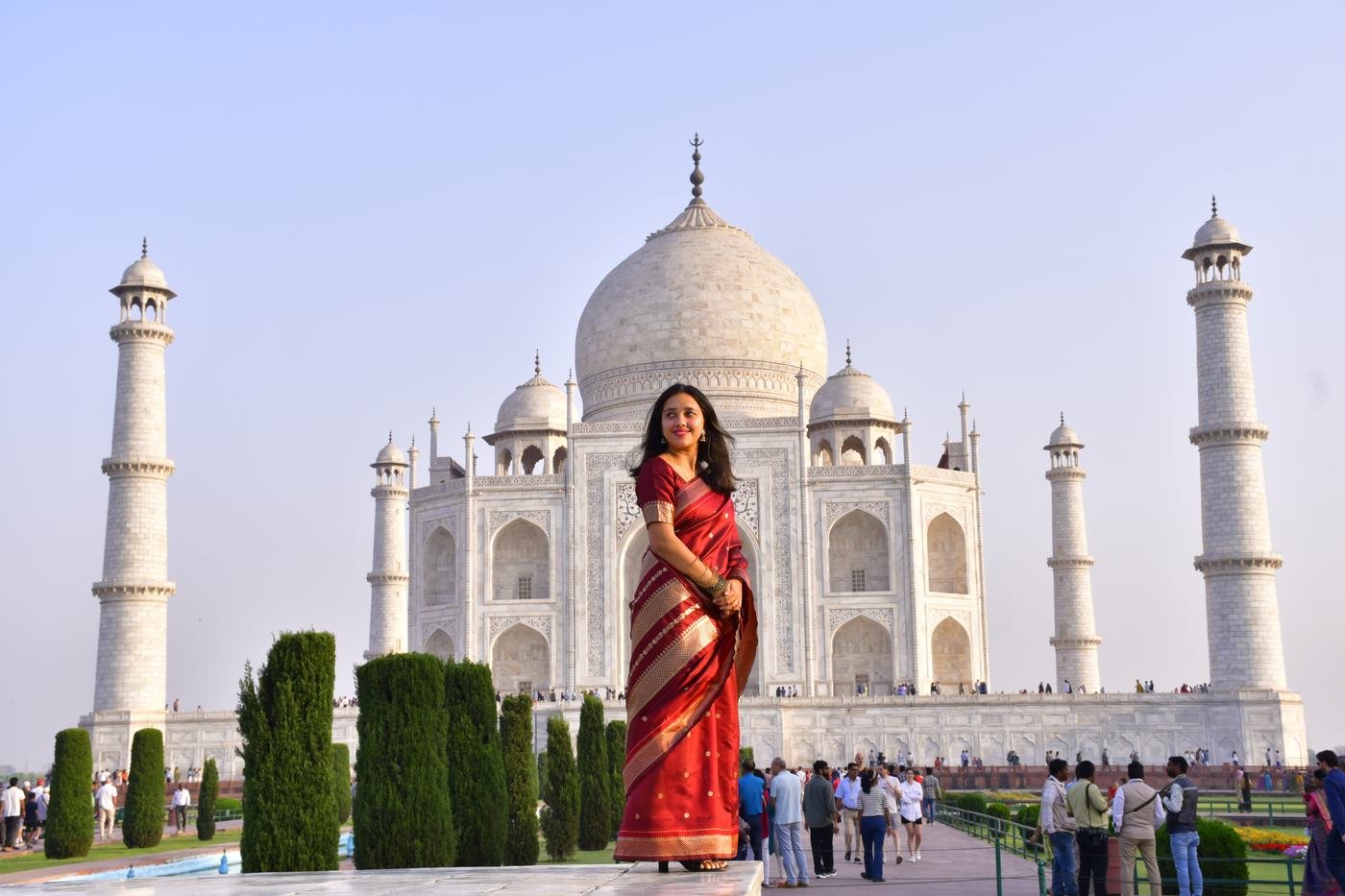 A traveller in a red saree posed in front of the Taj Mahal